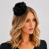 Woman wearing a black flower headpiece against a plain background
