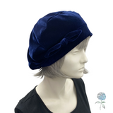 Navy blue velvet hat with bow on a mannequin head against a white background