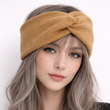 Woman wearing a mustard yellow headband with long wavy hair on a white background