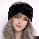 Woman wearing a black velvet headband with long, wavy hair against a white background