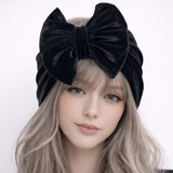 Woman wearing a black velvet headband with a bow on a white background