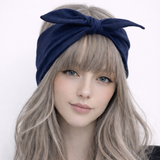 Woman wearing a navy blue headband with a bow on a white background