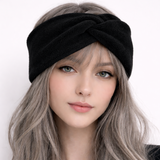 Woman wearing a black headband with long, wavy hair against a white background