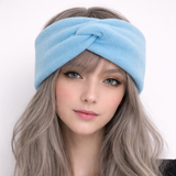 Woman wearing a light blue headband with a plain background