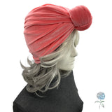 Coral turban on a mannequin head with gray hair against a white background