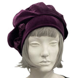 Mannequin head wearing a purple beret with a bow on a white background