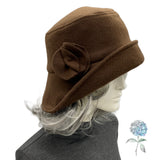 Brown felt hat with a flower on a mannequin head against a white background