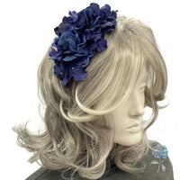 Mannequin head with wavy blonde hair wearing a blue floral headband on a white background
