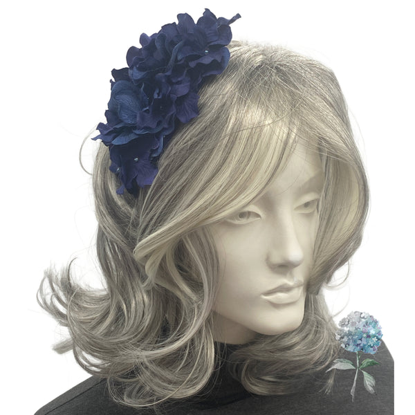 Mannequin head with wavy blonde hair wearing a navy blue floral headband on a white background.