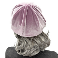 Pink velvet beanie worn by a person with gray hair on a white background