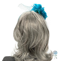 Person with gray hair wearing a blue floral headband on a white background