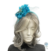 Mannequin head with gray hair wearing a blue floral headband on a white background