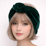 Woman wearing a green velvet turban against a white background