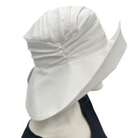 Wide brim linen derby hat handmade in white linen shown modeled on a hat mannequin, wide brim drama and elegance side view Boston Millinery 