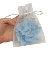 Pale blue hydrangea flower hair clip fascinator shown in organza pouch