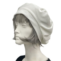 Winter white velvet beret with a pretty hydrangea petal brooch handmade in velvet and satin. modelled on a hat manequin boston millinery 