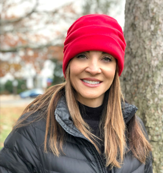Red Fleece Beanie lined in satin shown on a model standing by a tree