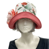 Eleanor cloche hat with a wide front brim for women handmade in dusky coral linen and a floral cotton accent band finished with a coral green and white peony flower brooch - front view