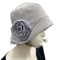 Handmade Gray Linen 1920s Style cloche hat with wide front brim and chiffon flower brooch. Modeled on a mannequin head. Side view showing the brooch. Boston Millinery