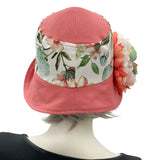 Boston Millinery's Eleanor cloche hat with a wide front brim for women handmade in dusky coral linen and a floral cotton accent band finished with a coral green and white peony flower brooch rear view