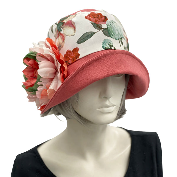 Boston Millinery's Eleanor cloche hat with a wide front brim for women handmade in dusky coral linen and a floral cotton accent band finished with a coral green and white peony flower brooch 