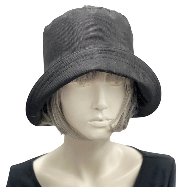 Black showerproof rain hat handmade in black polyester and lined in cotton shown modeled on a hat mannequin . Boston Millinery The Eleanor 