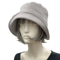 Handmade Gray Linen 1920s Style cloche hat with wide front brim and chiffon flower brooch. Modeled on a mannequin head. Plain side view Boston Millinery
