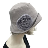 Handmade Gray Linen 1920s Style cloche hat with wide front brim and chiffon flower brooch. Modeled on a mannequin head. Side view showing the brooch. Boston Millinery