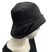 Black showerproof rain hat handmade in black polyester and lined in cotton shown modeled on a hat mannequin . Boston Millinery The Eleanor  side view