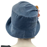 Boston Millinery's handmade Alice cloche in soft blue heavy velvet with contrasting hydrangea brooch modeled on a hat mannequin rear view