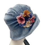 Boston Millinery's handmade Alice cloche in soft blue heavy velvet with contrasting hydrangea brooch modeled on a hat mannequin side view