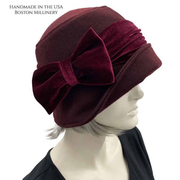 Cloche Hat the Eleanor narrow front brim dark burgundy eggplant wool with velvet band and square bow handmade by Boston Millinery  modeled on a hat stand bow side view 